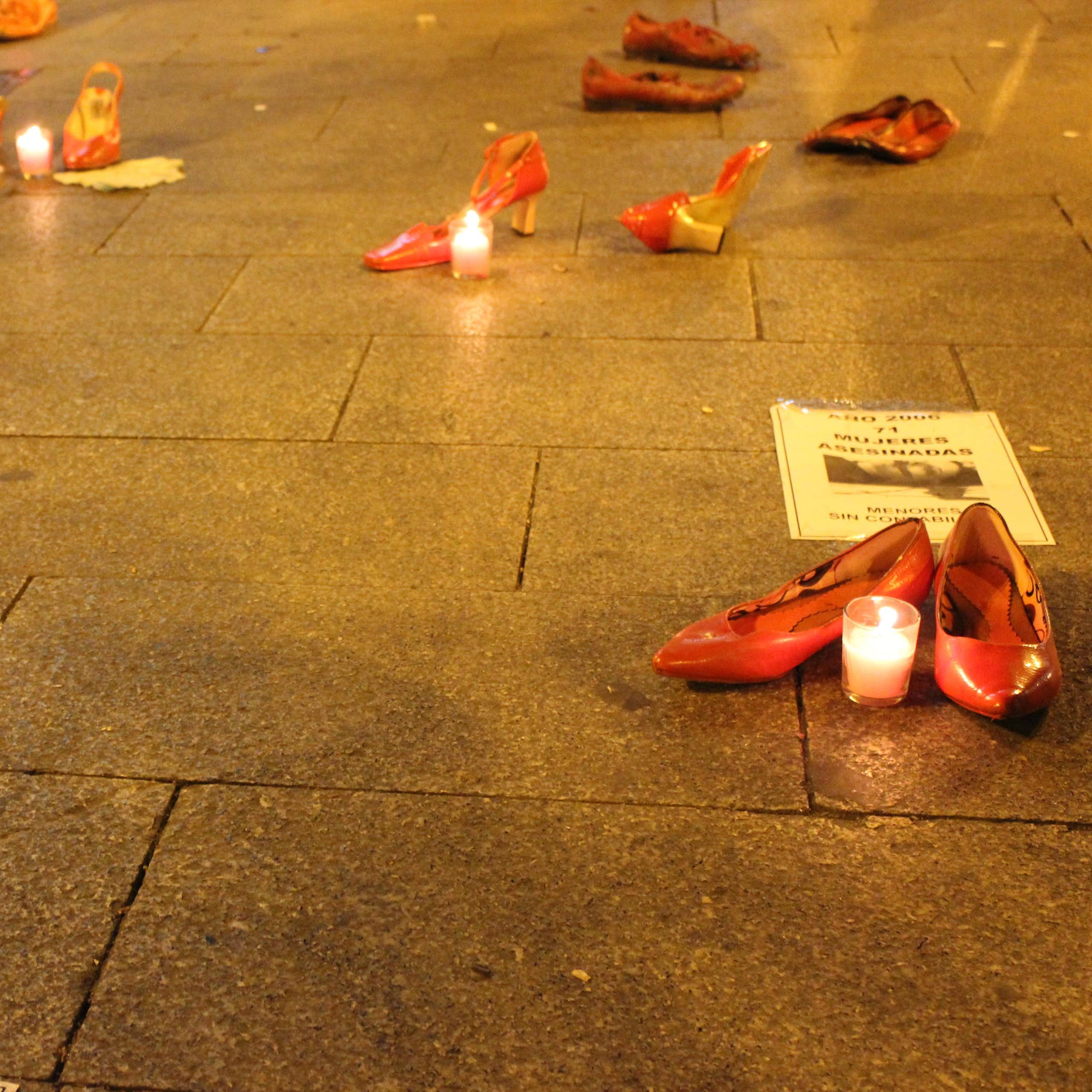 Zapatos rojos con velas en el suelo en señal de protesta.