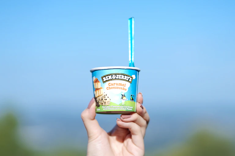 Tub of Ben & Jerry's being held up against the sky