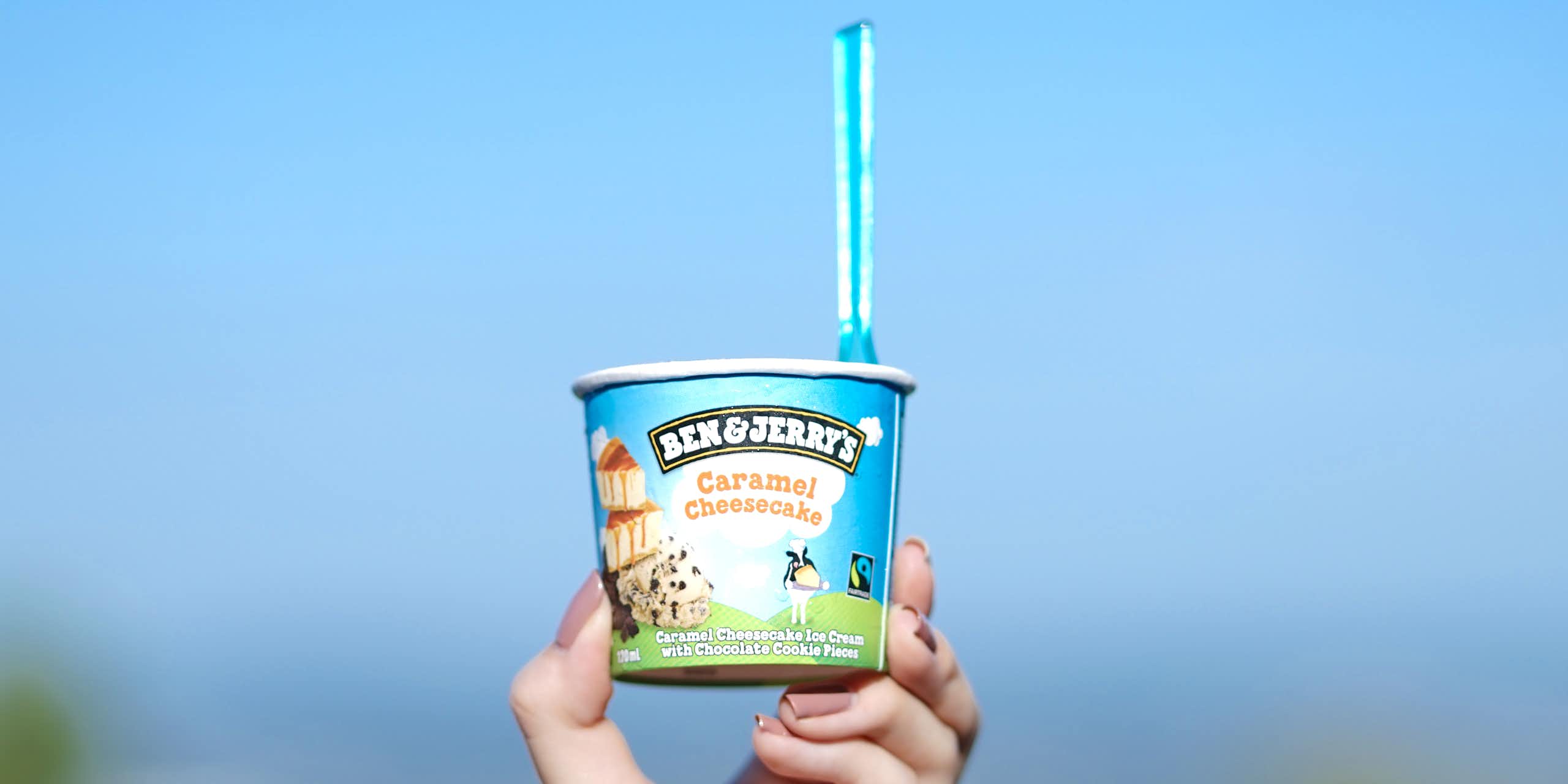 Tub of Ben & Jerry's being held up against the sky