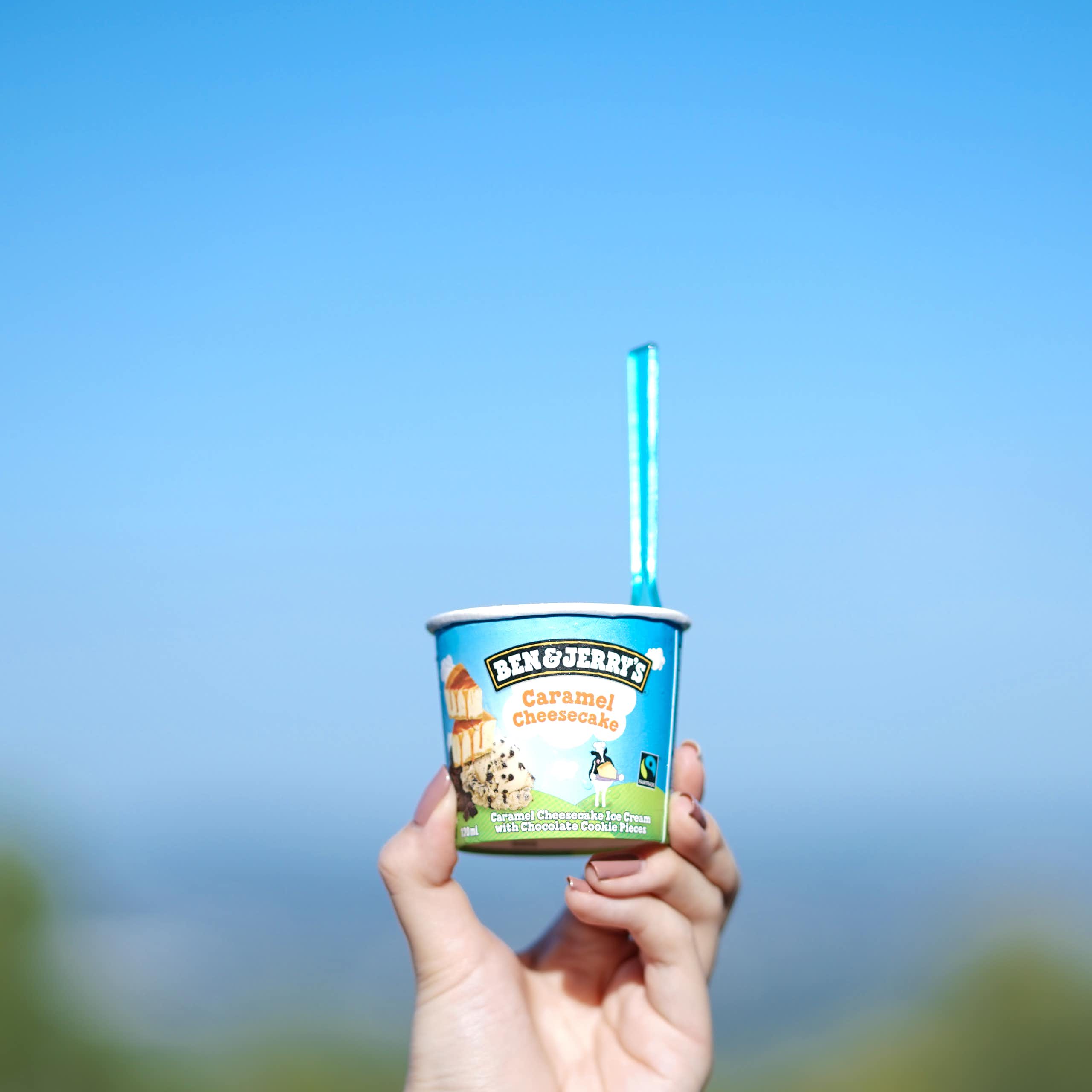 Tub of Ben & Jerry's being held up against the sky