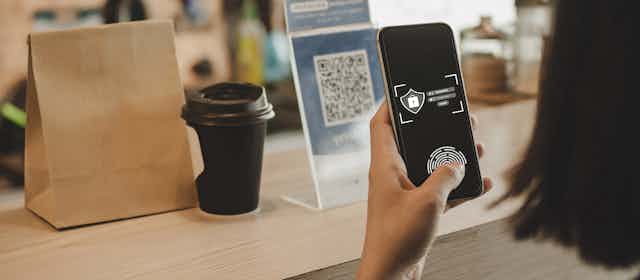 The hand of a customer using a mobile phone to scan a QR code in a coffee shop. 