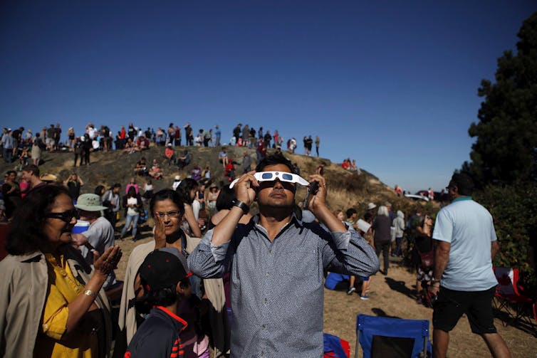 People seen looking up at the sky wearing eclipse glasses.