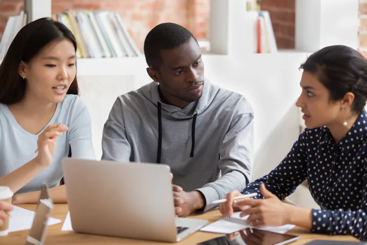 Three young people with laptop discussing together