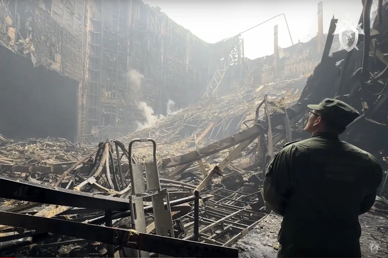 Un homme en treillis militaire observe un immeuble en ruines