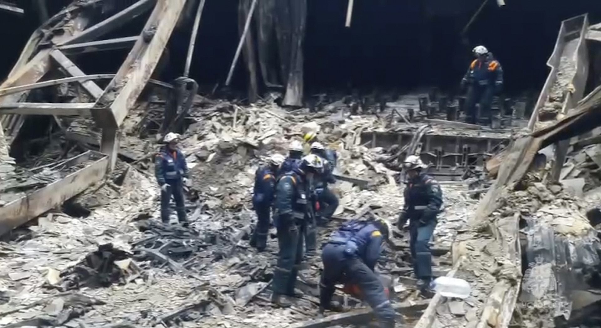 Des hommes s’affairent dans les ruines d’un immeuble