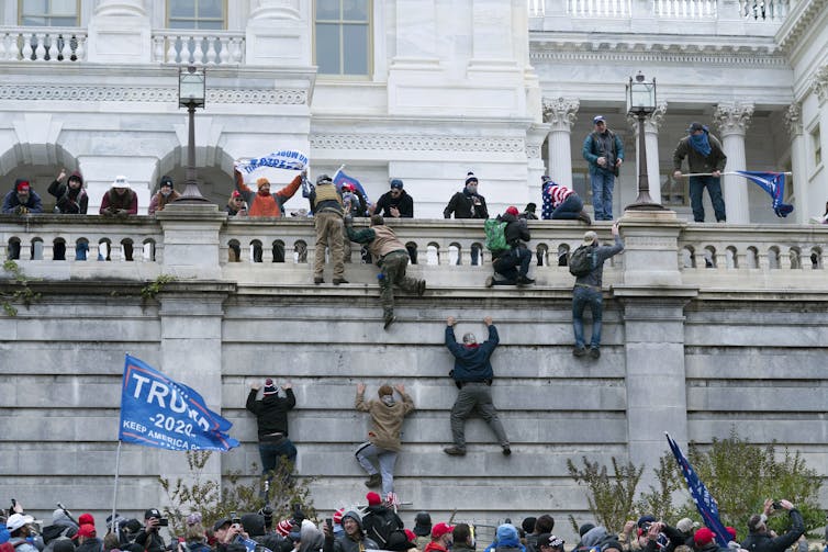 Los alborotadores escalan los muros del Capitolio de Estados Unidos el 6 de enero de 2021.