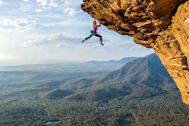 A woman hanging from a sheer rock face