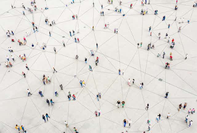 Aerial view of a sparse crowd standing on pavement, with each person connected by lines