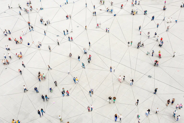 Aerial view of a sparse crowd standing on pavement, with each person connected by lines