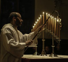 A priest extinguishes a candle.