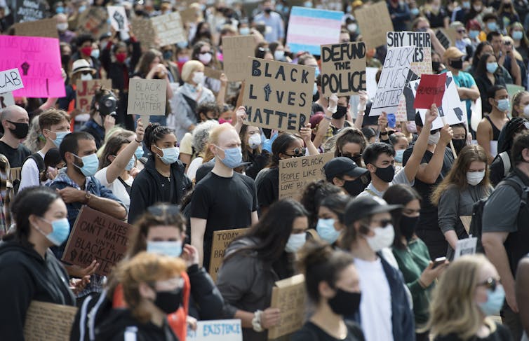 People at a demonstration, with one sign seen saying 'Black Lives Matter.'