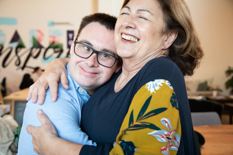 An adult man with down syndrome hugs his mum