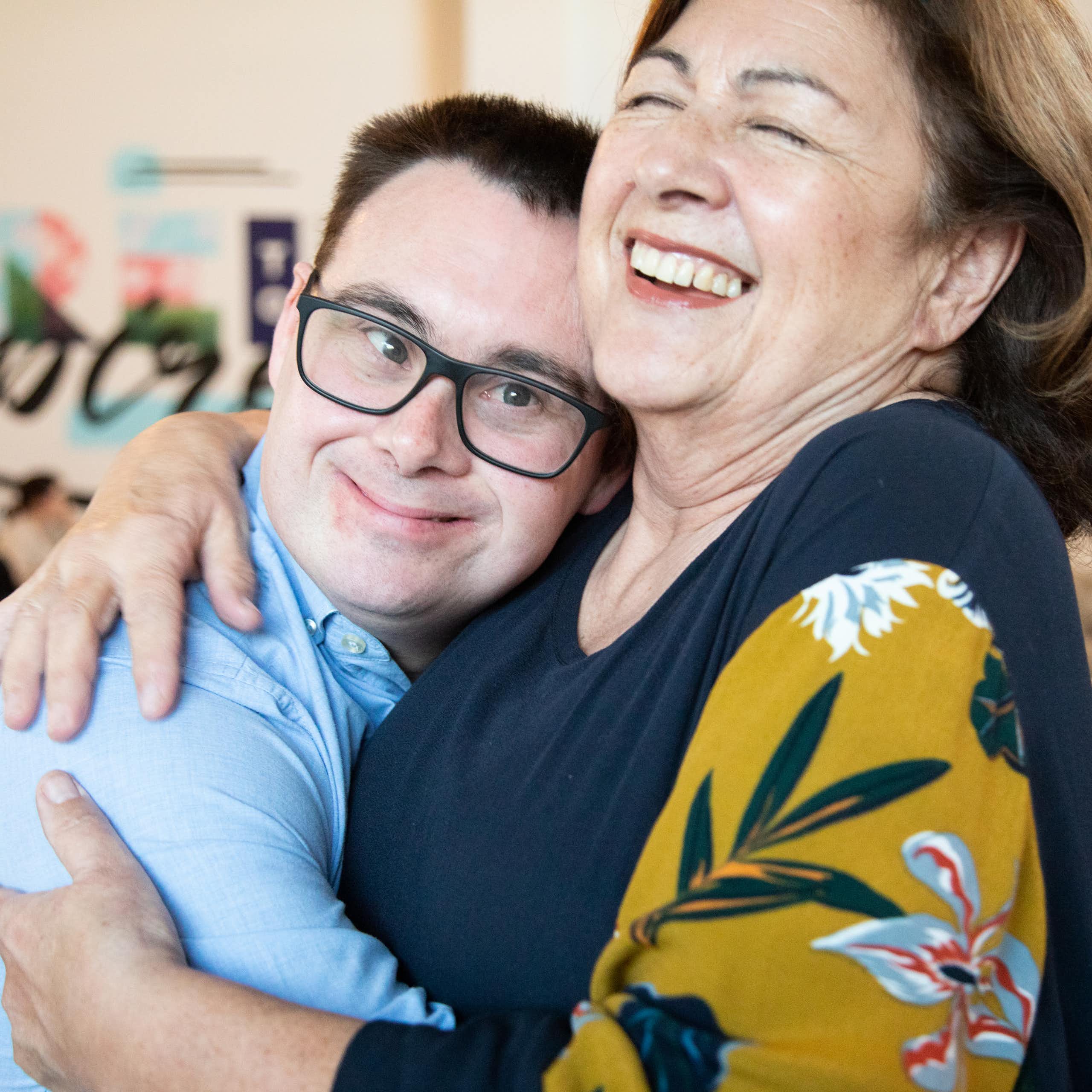 An adult man with down syndrome hugs his mum
