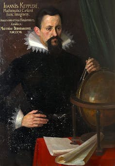 The man with black hair and a beard is dressed in black with elaborate collars and has one hand on his hip and the other on a globe.
