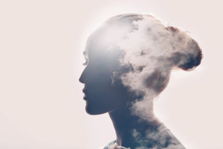 Collage of a photo of a silhouette of a woman's head with clouds.