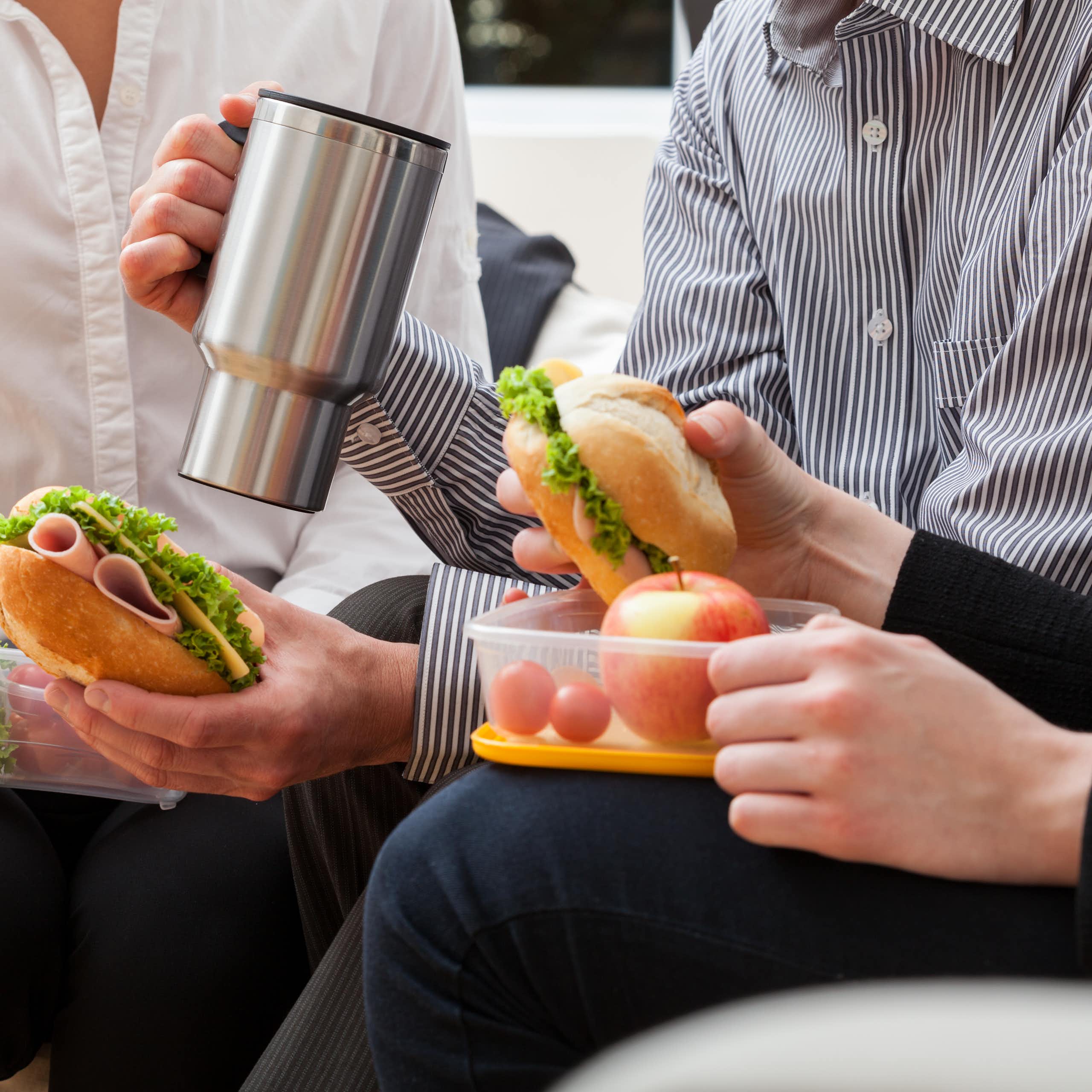 Photo of three colleagues eating sandwiches out of tupperware, sitting side by side