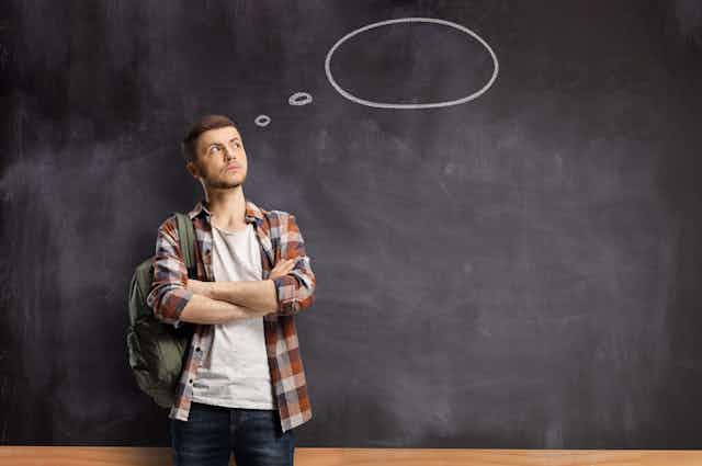 Young man with a blank thought bubble behind him on a chalkboard