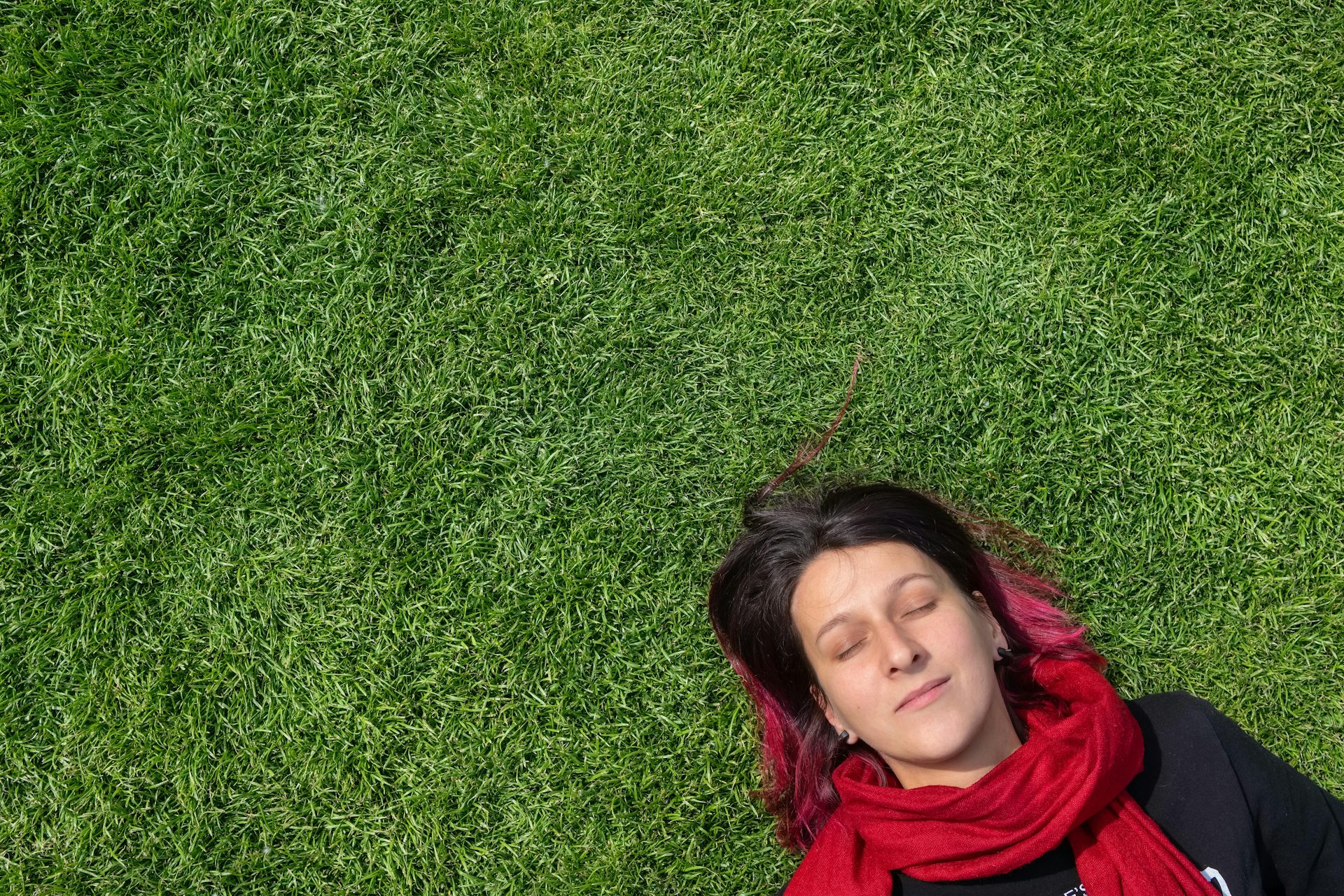 A woman lying on grass, sleeping.