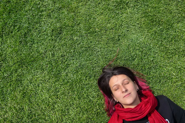 A woman lying on grass, sleeping.