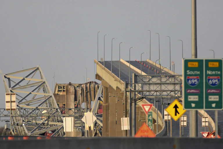 A bridge with a large missing section and pieces next to it in the water