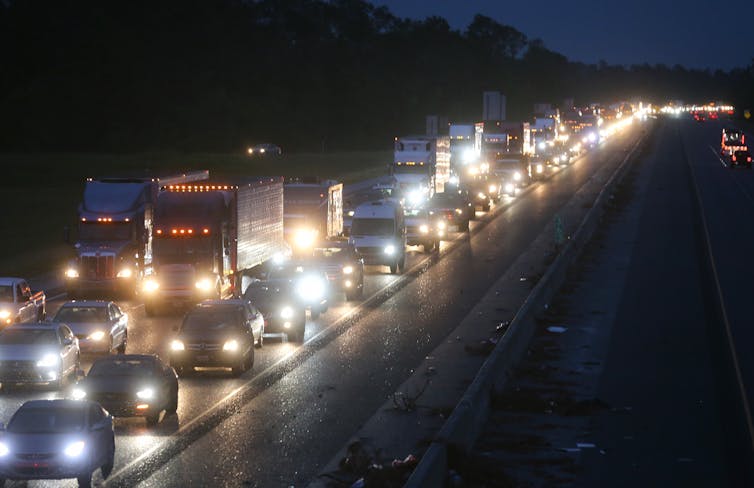 A highway at night, jammed with traffic on one side, the other side empty.