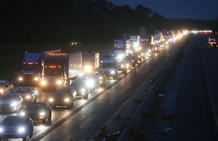 A highway at night, jammed with traffic on one side, the other side empty.