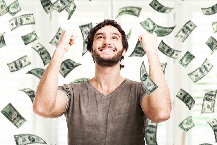 Man punching the air as cash notes float in the air.