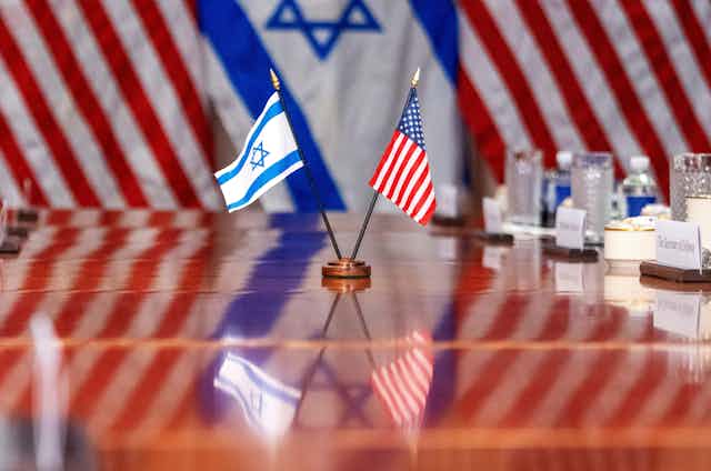 Israeli and US flags together on a polished boardroom table.
