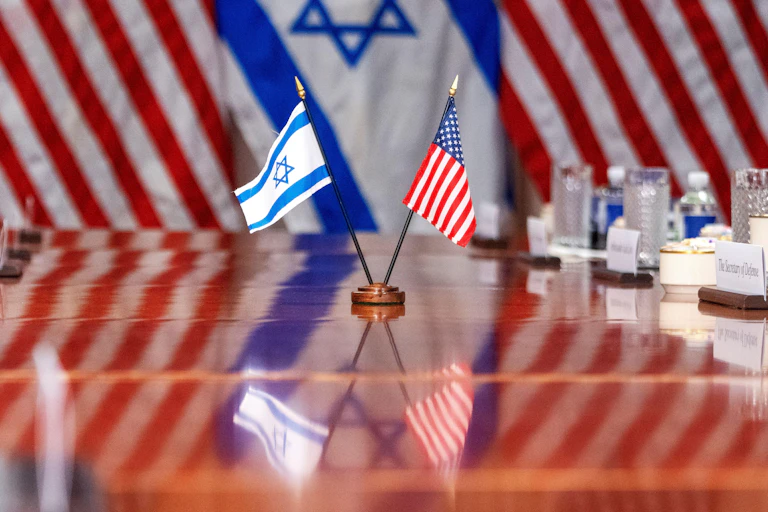 Israeli and US flags together on a polished boardroom table.