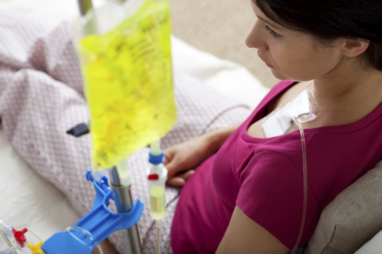 Over the shoulder view of chemotherapy IV bag connected to a port on a patient's chest