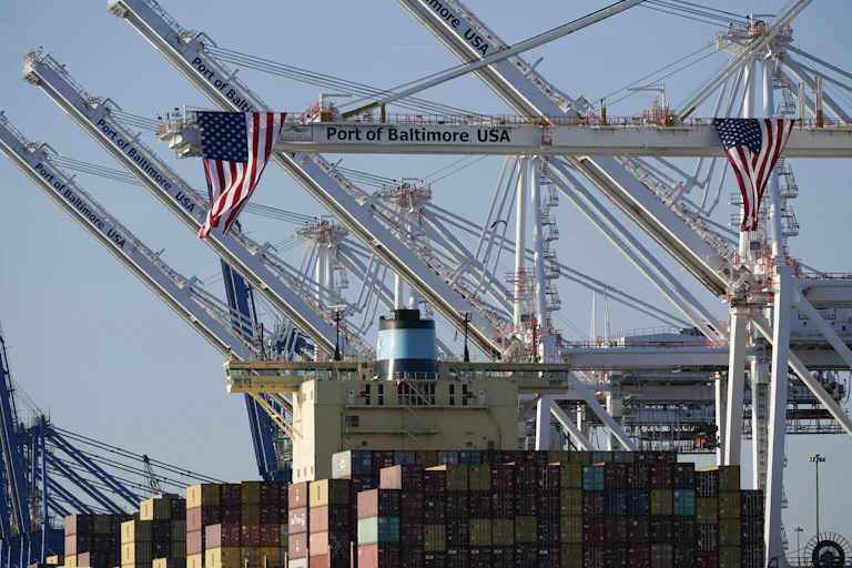 American flags hang off cranes with one reading Port of Baltimore USA.
