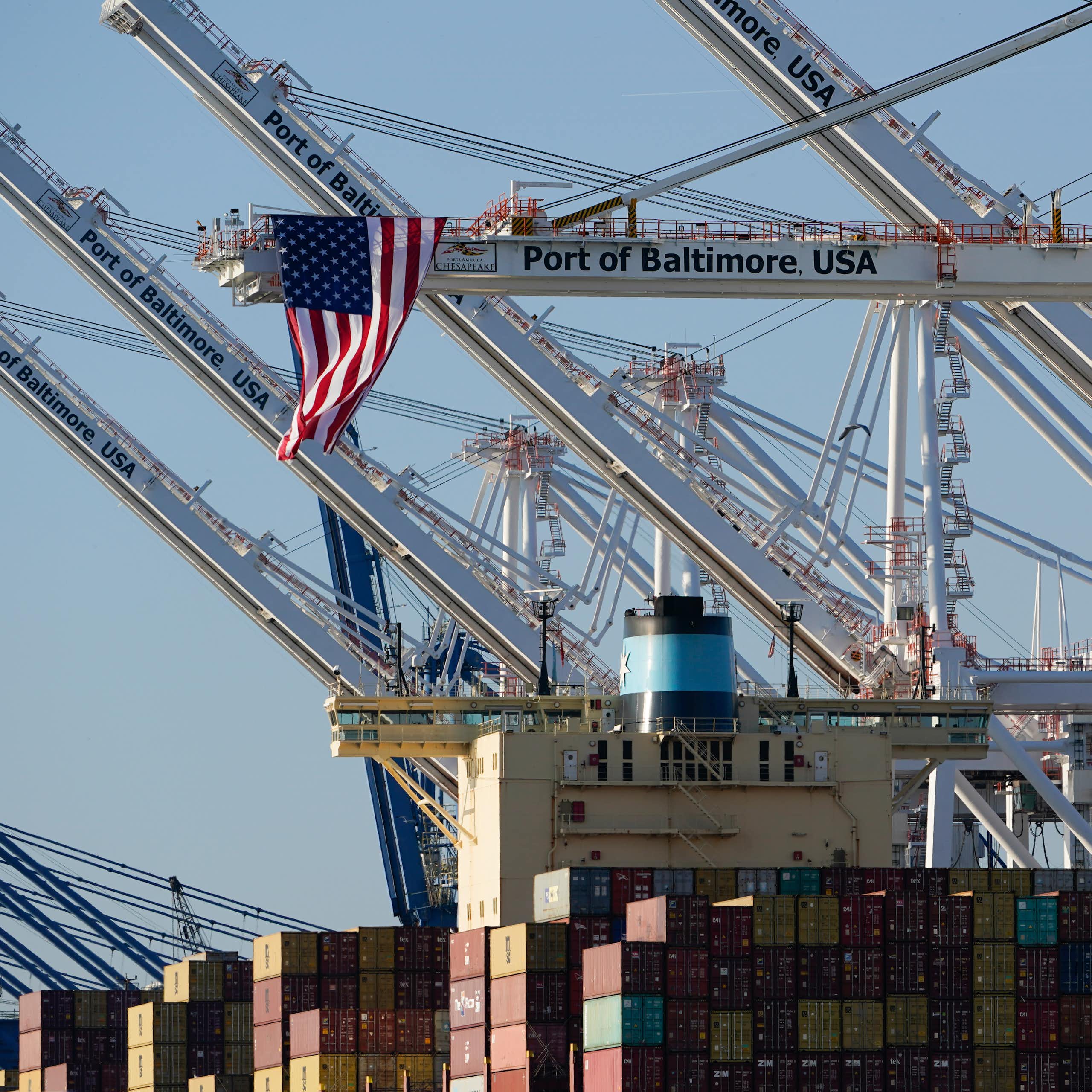 American flags hang off cranes with one reading Port of Baltimore USA.