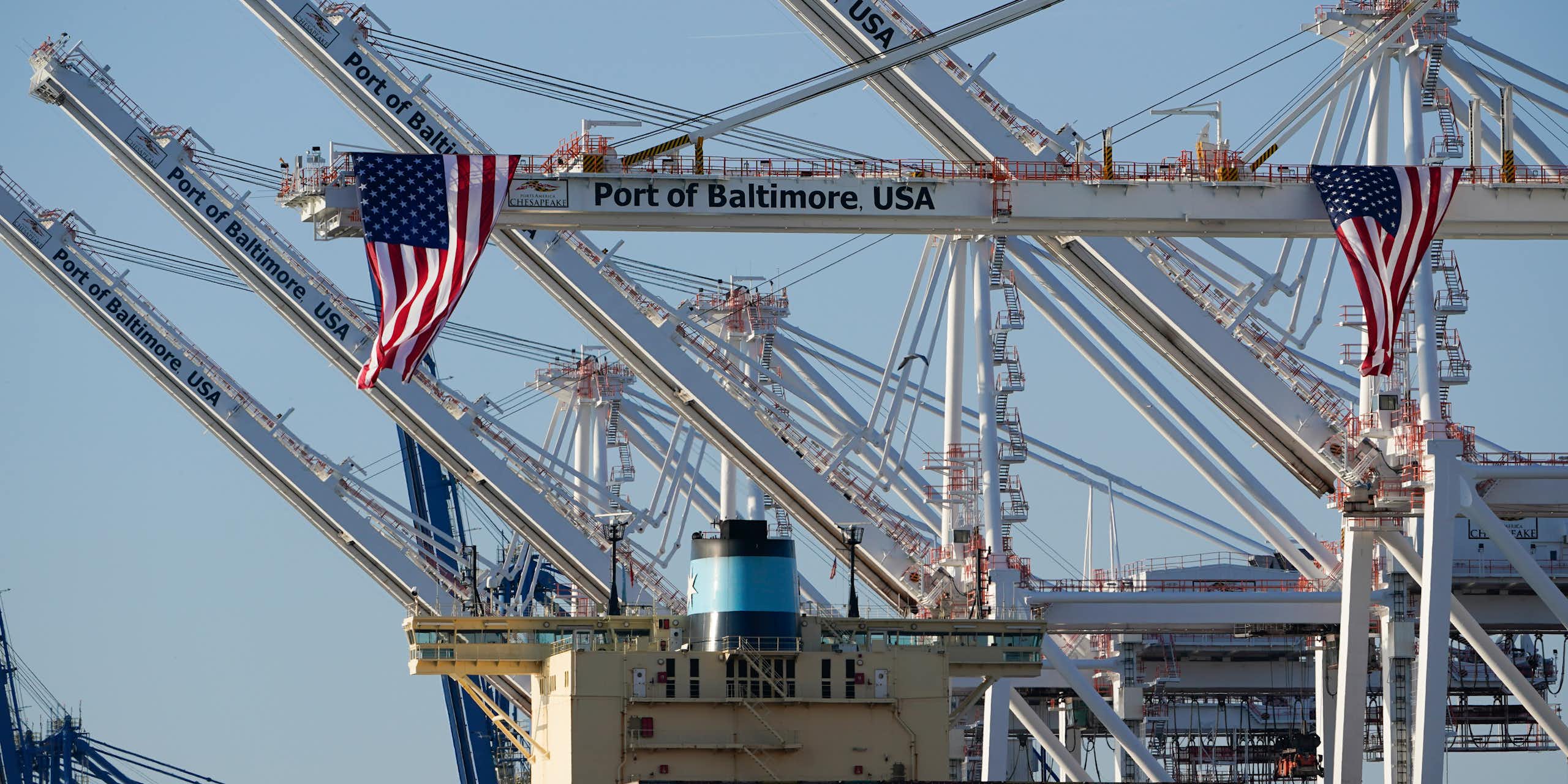 American flags hang off cranes with one reading Port of Baltimore USA.