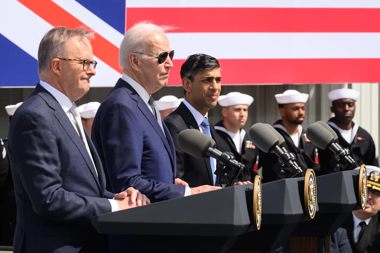Australian Prime Minister Anthony Albanese (L), US President Joe Biden (C) and British Prime Minister Rishi Sunak (R) stand in front of podiums ahead of a press conference.
