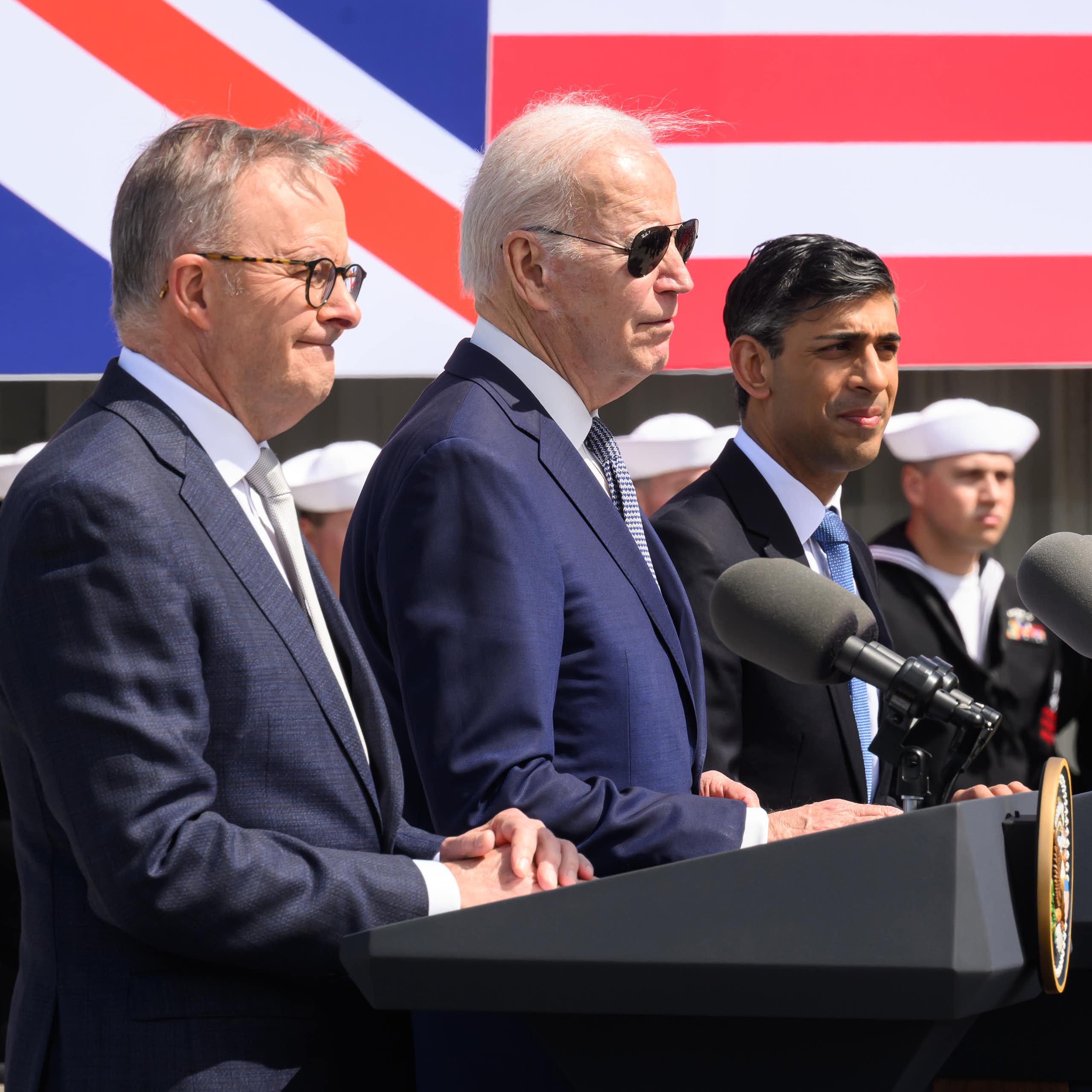 Australian Prime Minister Anthony Albanese (L), US President Joe Biden (C) and British Prime Minister Rishi Sunak (R) stand in front of podiums ahead of a press conference.