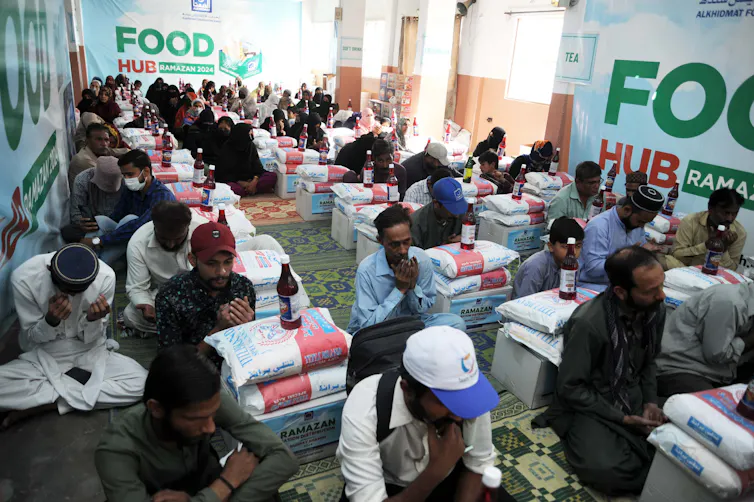 A group of men kneel and pray next to their bags of rations.