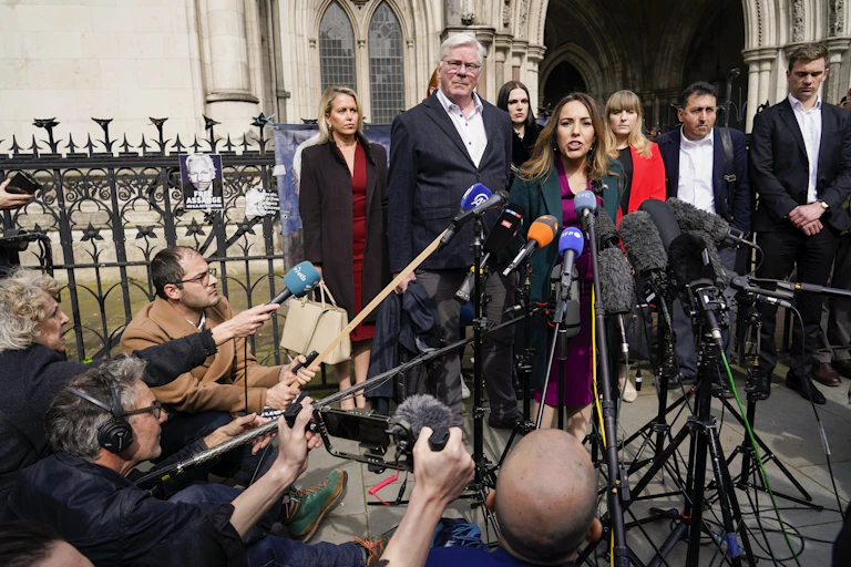 Woman surrounded by microphones speaks to media outside courthouse