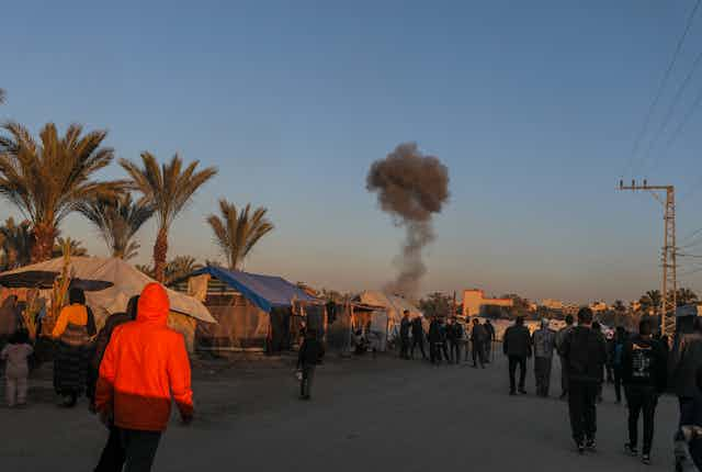 Palestinians watch an Israeli airstrike in southern Gaza, March 25 2024.