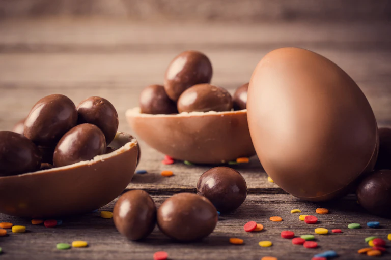 Plusieurs oeufs en chocolat de différentes tailles empilés sur une table en bois