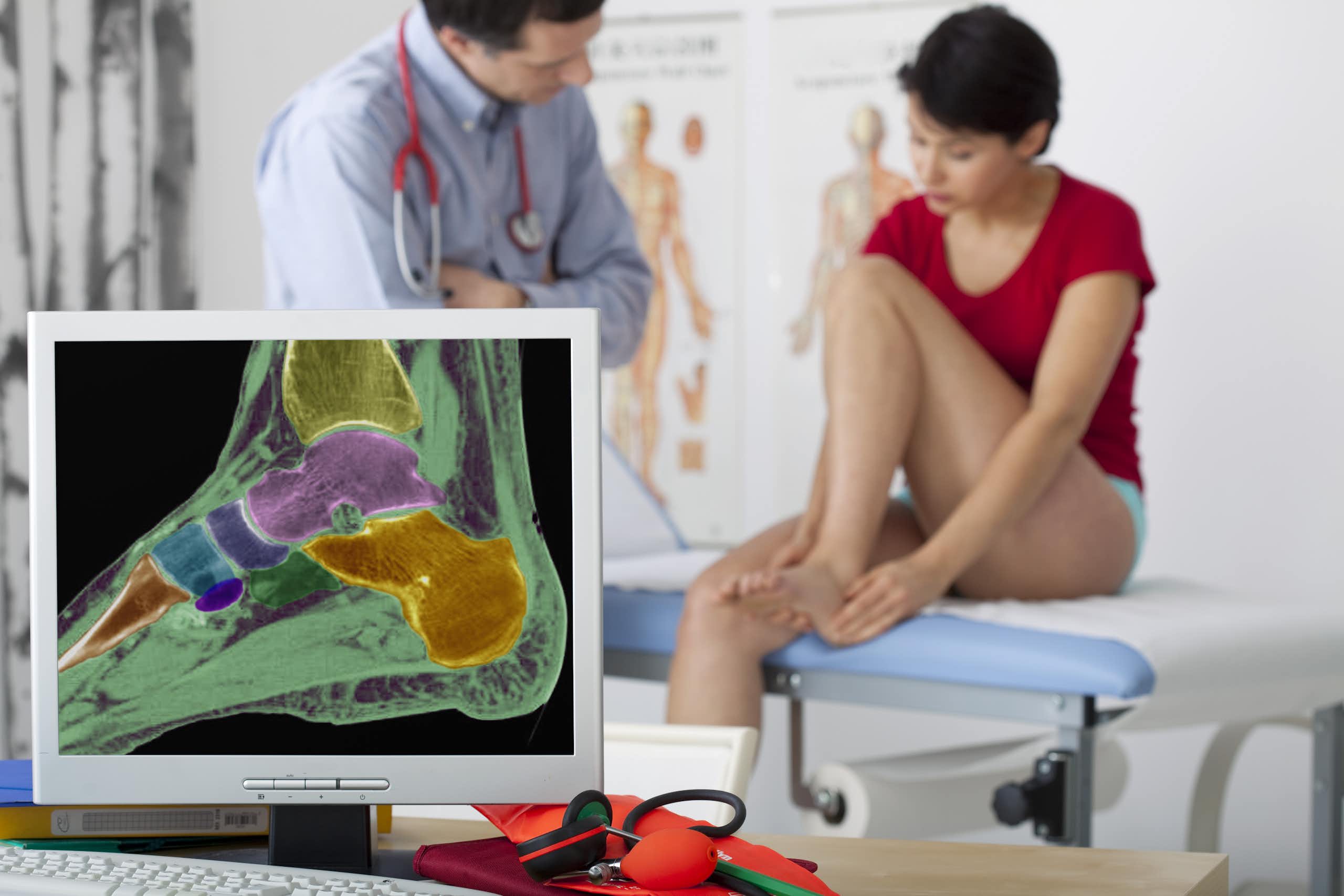 Une femme est en consultation avec un médecin à qui elle montre sa cheville. Au premier plan, on voit une radiographie de sa cheville.