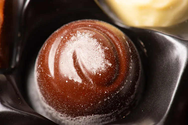 Motif circulaire de couleur plus claire, l’efflorescence, à la surface d’un bonbon de chocolat brun