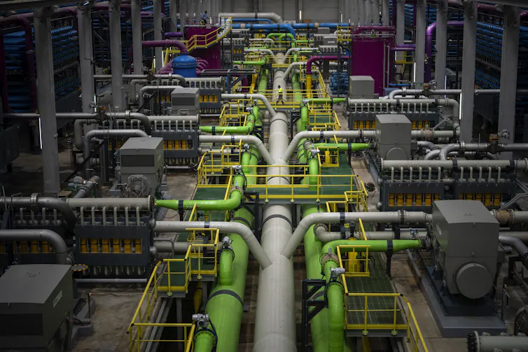 A man walks amongs a network of pipes.