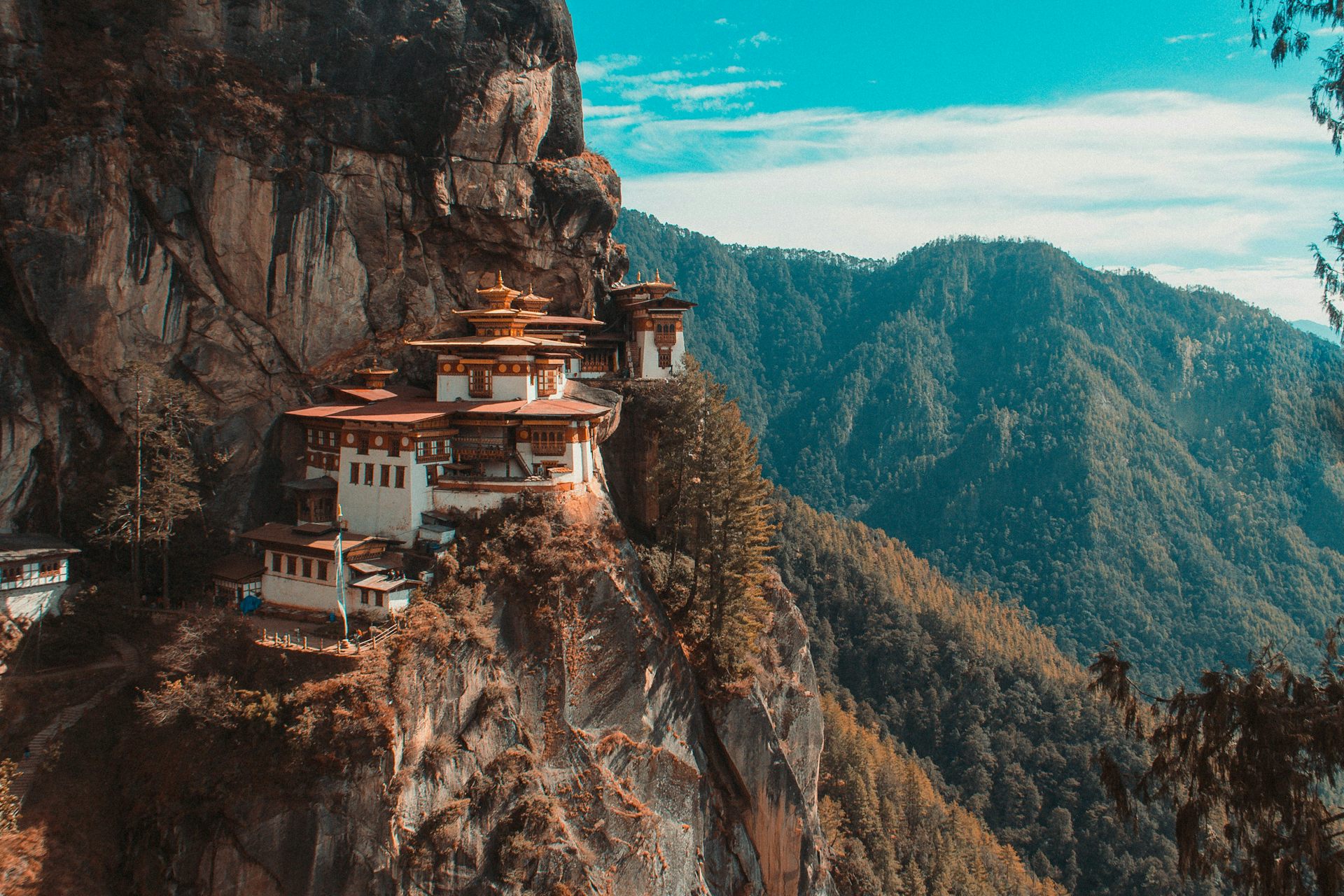 Le temple de Paro Taktsang, niché à flanc de falaise, dans un paysage de reliefs forestiers typique du Bhoutan