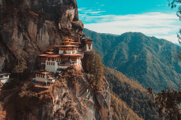 Le temple de Paro Taktsang, niché à flanc de falaise, dans un paysage de reliefs forestiers typique du Bhoutan