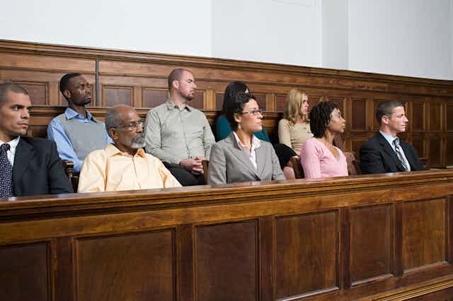 stock image of nine people in a jury box, listening to a speaker off-camera.