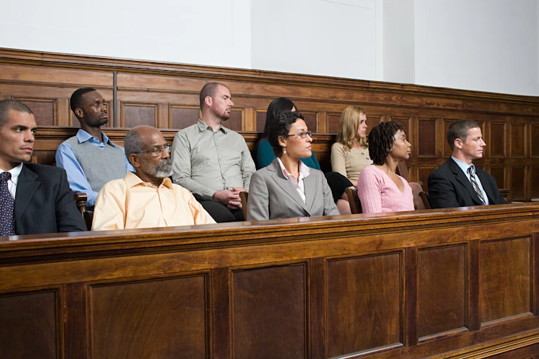 stock image of nine people in a jury box, listening to a speaker off-camera.