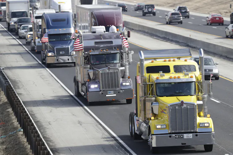 Semi-trucks drive on a highway