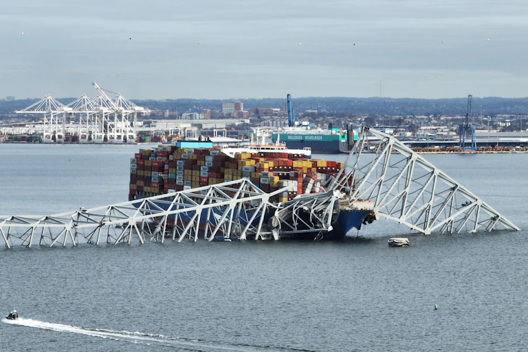 A cargo ship is ensnared in a mangled steel bridge.