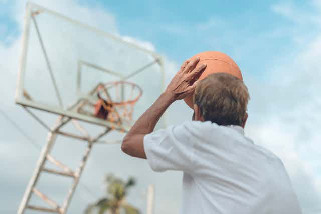 homem lança uma bola de basquete rumo à cesta