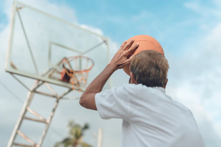homem lança uma bola de basquete rumo à cesta